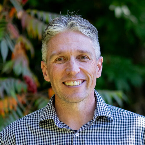 man wearing checked shirt smiling at camera