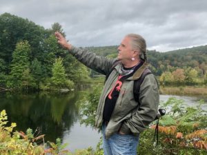 Man gesturing while speaking with a river behind him