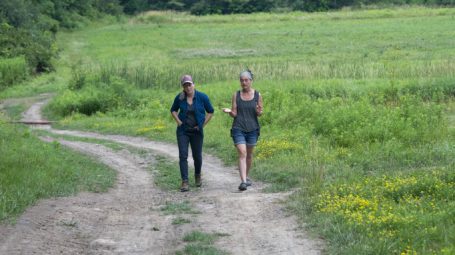 two women talking and walking on a path through a farm - vermont