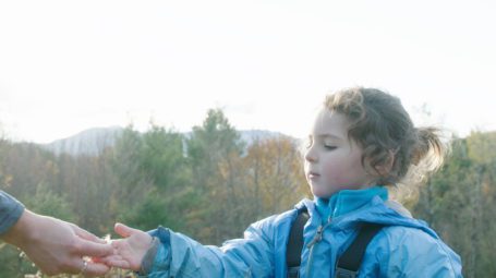 child in late fall field looking at seed pod