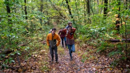 group of people walking in the woods on a trail in what will hopefully become the Monkton Town Forest