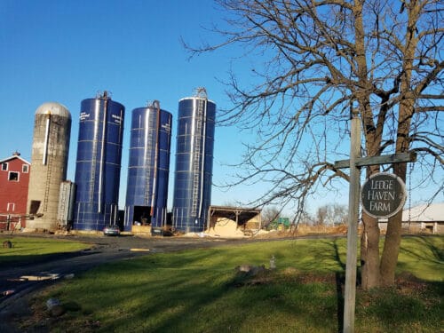 farmstead with three blue silos, barn to the left, and farm sign reading 'Ledge Haven Farm' in foreground. Orwell Vermont