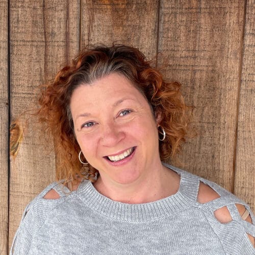 woman smiling at camera with wood paneling behind her. Vermont