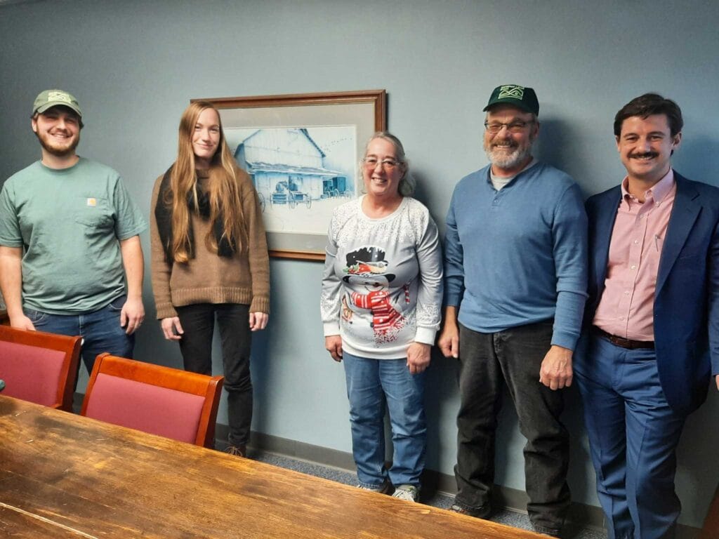 Three white men and and two white women pose for a photo in a conference room