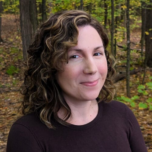 Photo of woman smiling in front of forest view