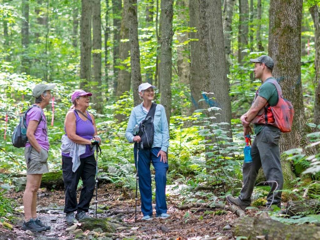 People standing and talking on a path through woods. Hinesburg Town Forest Vermont