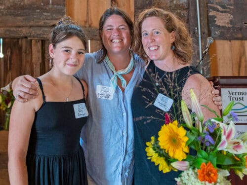 Three people smiling at camera with a vase of flowers to the right. Sara Donegan of Trillium Hill Farm with VLT's Maggie Donin, Eric Rozendaal Memorial Award 2024