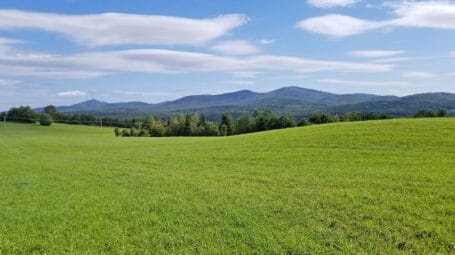 Rolling farm fields on sunny day, with hills in background. Washington Vermont. Lambert Farm