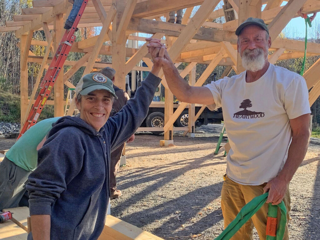 A white woman and a white man stand holding hands near a building under construction