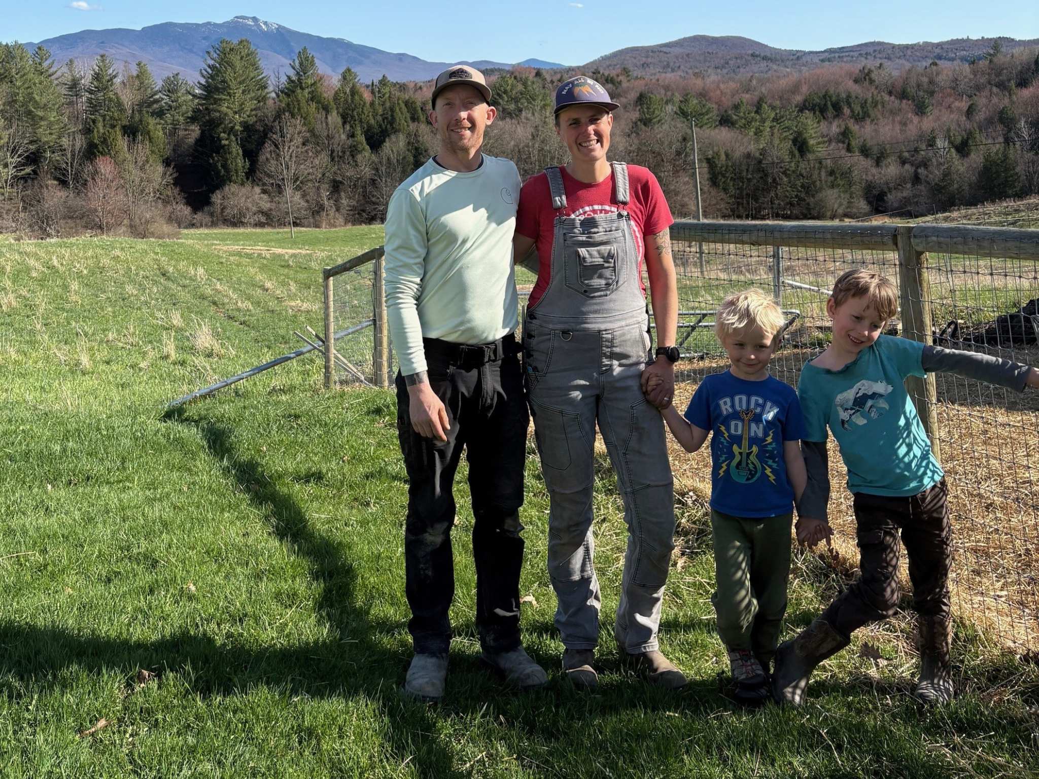 A man, a woman, and two young boys, standing on a farm field.