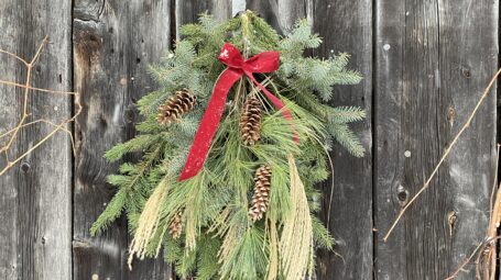 A evergreen swag hangs on a rough-sided barn.