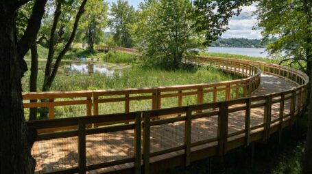A boardwalk curves with water in the background