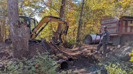 An excavator and a dump truck work on a culvert.