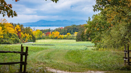 fall view of open pasture with Lake Champlain and mountains beyond.