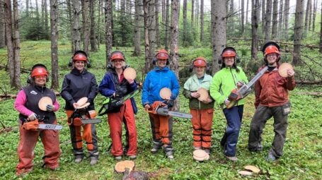 Seven Game of Logging participants pose with recently cut "tree cookies".